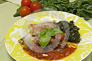 Meat rolls in tomato sauce served with spinach