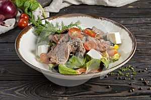 Meat salad with roast beef and feta cheese. Cold appetizer of lettuce leaves, cherry tomatoes, beef, veal or pork, feta cheese and