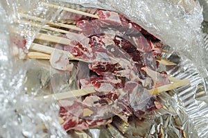 Meat sausages on wooden skewers in Ð°luminium packaging and cellophane