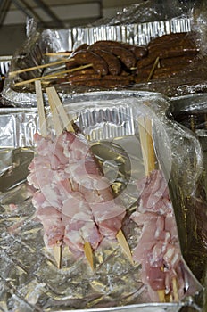 Meat sausages on wooden skewers in Ð°luminium packaging and cellophane