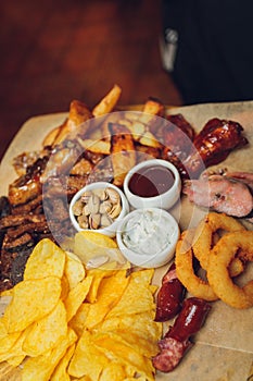 Meat set on a wooden board. Fried chicken wings, pork ribs, grilled vegetables, french fries. Beer appetizer with sauces