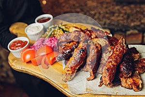 Meat set on a wooden board. Fried chicken wings, pork ribs, grilled vegetables, french fries. Beer appetizer with sauces