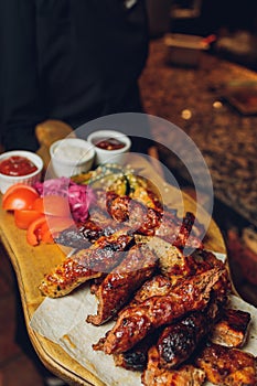 Meat set on a wooden board. Fried chicken wings, pork ribs, grilled vegetables, french fries. Beer appetizer with sauces