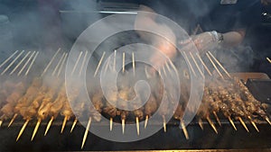 Meat skewers being cooked on hot charcoal bed