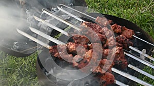 meat on skewers on a grill with coals and smoke