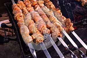 Meat skewers grill. Pork or beef are fried on open fire. Barbecue kitchen party close up image. Kebab or shashlik cooking on spits