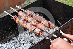 Meat skewers grill. Pork or beef are fried on open fire. Barbecue kitchen party close up image. Kebab or shashlik cooking on spits