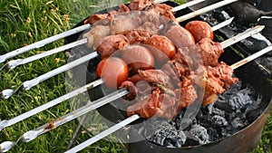 meat on skewers tomatoes on the grill with coals.