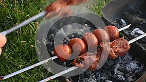 meat on skewers tomatoes on a metal grill with coals in nature.