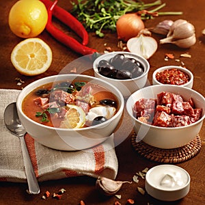 Meat Solyanka soup on with ingridients, sausage, olive,lemon, parsley, garlic, yogurt. Ukrainian food. Wooden background