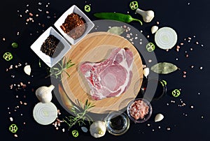 Meat steak on a cutting board and pepper, bay leaf, rosemary, onions, salt, olive oil, soy sauce