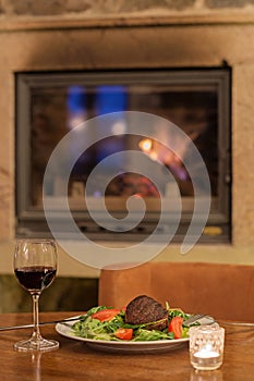 meat steak with vegetables and red wine, a burning fireplace