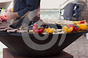 Meat, steaks and sausages with vegetables cooking on grill and smoldering coals. Barbecue