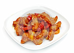 Meat in sweet and sour sauce and red pepper in a plate on a white background