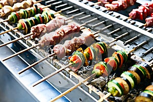 Meat and vegetable kebabs on skewers over coals on barbecue. BBQ grilled shish meat on skewers. Grilling pork or beef