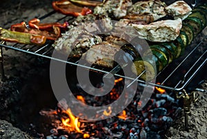 Meat and vegetable shish kabobs grilling on fire with flames.