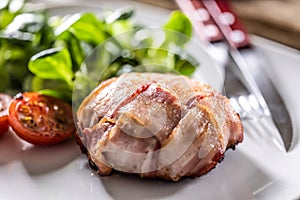 Meat wrapped in slices of bacon, baked until golden crispy and served with cherry tomatoes and green leave salad