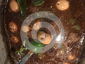 Meatball stew with bell peppers and eggs cooking on stove