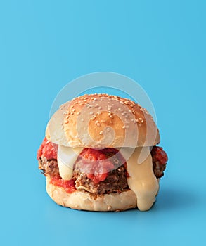 Meatballs burger with melted cheese, minimalist on a blue background