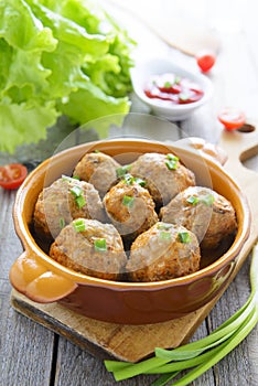 Meatballs in ceramic pan on wooden table