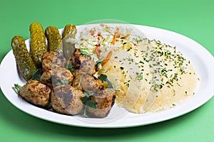 Meatballs with mashed potatoes pickles  in a plate bowl with greens vegetables