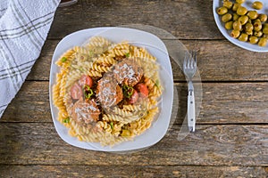 Meatballs with rotini pasta in white plate. Top view