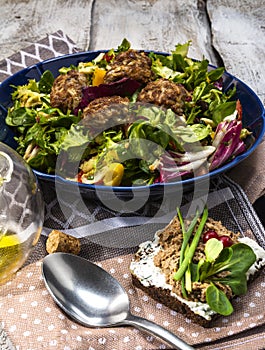Meatballs with salad on blue bowl on white wooden table. Tasty and healthy food with olive oil.