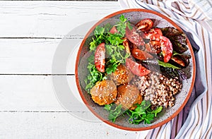 Meatballs, salad of tomatoes and buckwheat porridge on white wooden table. Healthy food. Diet meal. Buddha bowl. Top view.