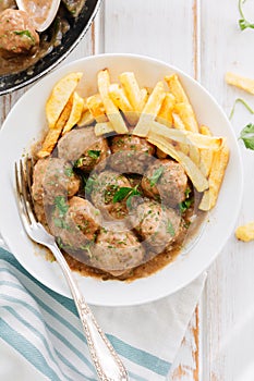 Meatballs in sauce with parsley and fries