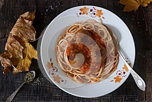 Meatballs in a sauce with pasta on a wooden background with autumn leaves. Rustic style.