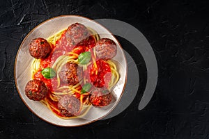 Meatballs with spaghetti, overhead shot on black photo