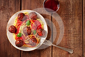 Meatballs with spaghetti and wine, overhead flat lay shot on a dark rustic wooden background