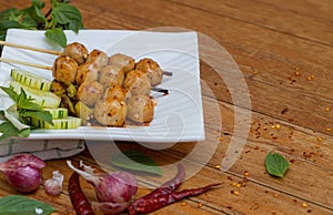 Meatballs toasted on wood dish and a sauce decorated with coriander placed on the table brown wood. Grill pork balls pour at