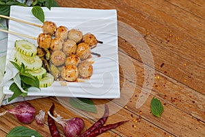 Meatballs toasted on wood dish and a sauce decorated with coriander placed on the table brown wood. Grill pork balls pour at