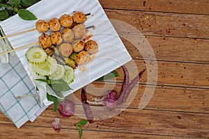Meatballs toasted on wood dish and a sauce decorated with coriander placed on the table brown wood. Grill pork balls pour at