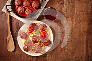 Meatballs with tomato sauce and pasta, with wine, overhead flat lay shot on a rustic wooden background