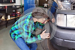 Mecanic checking car suspension system, at repair service station.