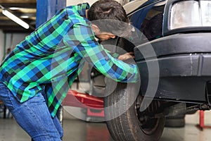Mecanic checking car suspension system, at repair service station.