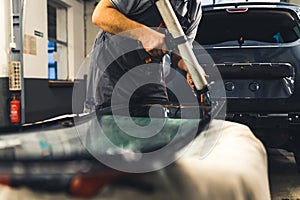 Mechanic adding glue to the windscreen of a car windshield replacement station