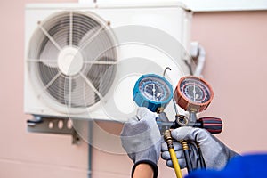 Mechanic air conditioner technician using manifold gauge checking refrigerant for filling home air conditioning