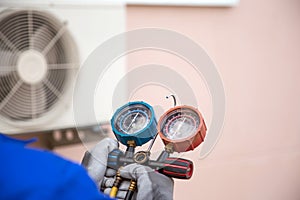 Mechanic air conditioner technician using manifold gauge checking refrigerant for filling home air conditioning