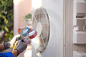 Mechanic air conditioner technician using manifold gauge checking refrigerant for filling home air conditioning and air duct