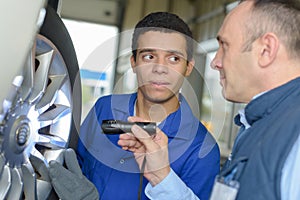 Mechanic with apprentice inspecting wheel with torch