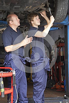 Mechanic and apprentice working on car