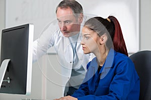 Mechanic and apprentice working on car with computer