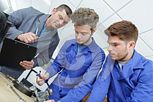 Mechanic and apprentice working on car part photo