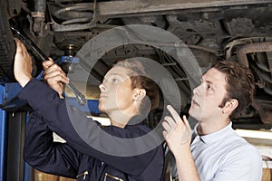 Mechanic And Apprentice Working On Car Together photo