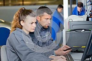 Mechanic and apprentice working on computer