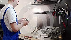 Mechanic assembles engine kit in workshop. Expert installs pistons, rings, liners. Automotive rebuild, motor maintenance