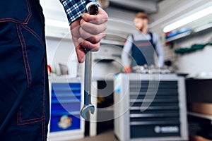 The mechanic in the auto service is standing with the instrument. Close-up photo of a mechanic`s hand with a wrench